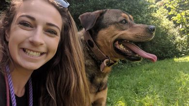 A girl outside with her dog looking happy.