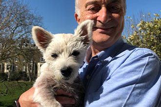 Sir Tony Robinson holding his westie in the sunshine.