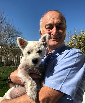Sir Tony Robinson holding his westie in the sunshine.